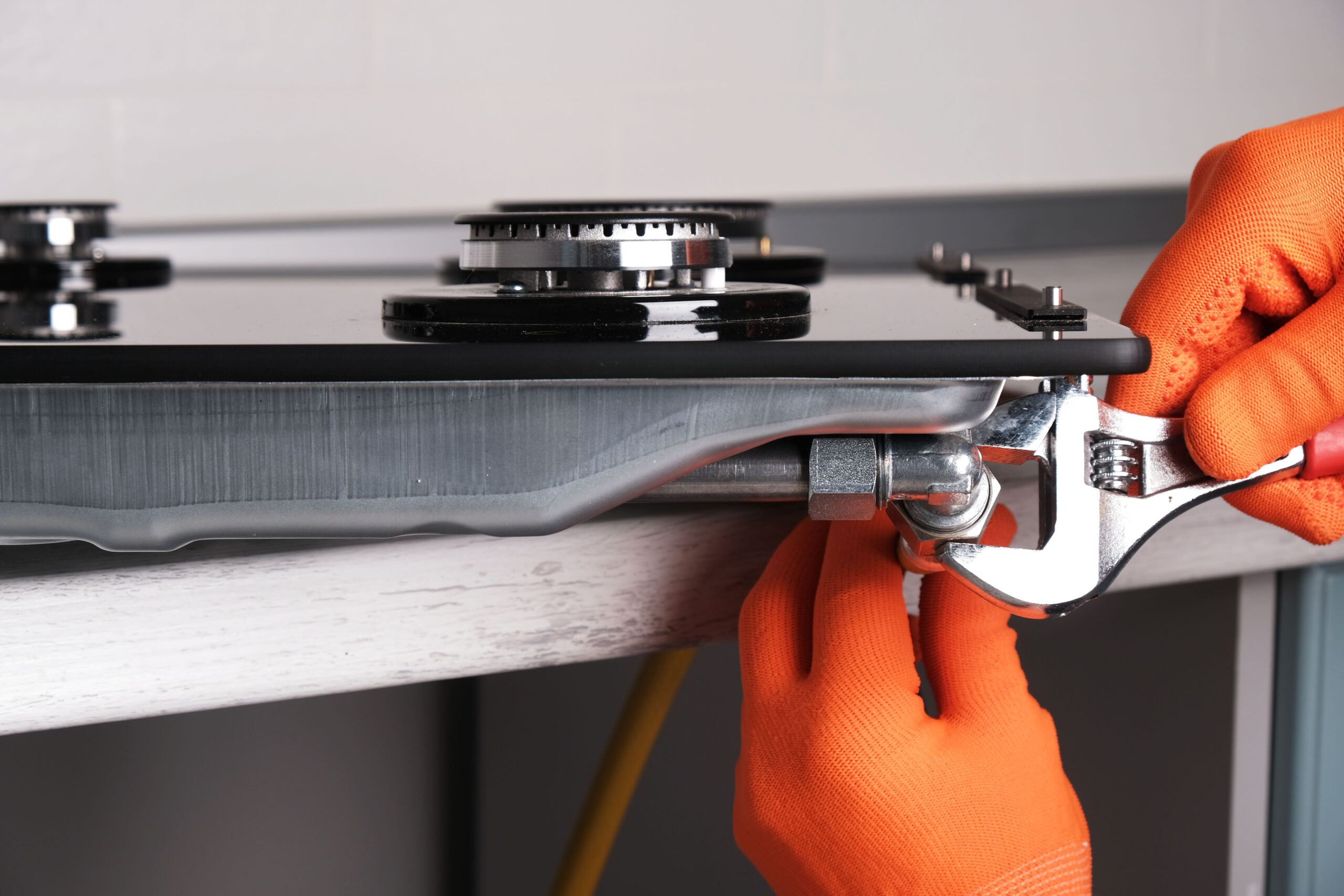 Connecting gas hose to hob Connecting gas hose to hob, hands with an adjustable wrench close-up